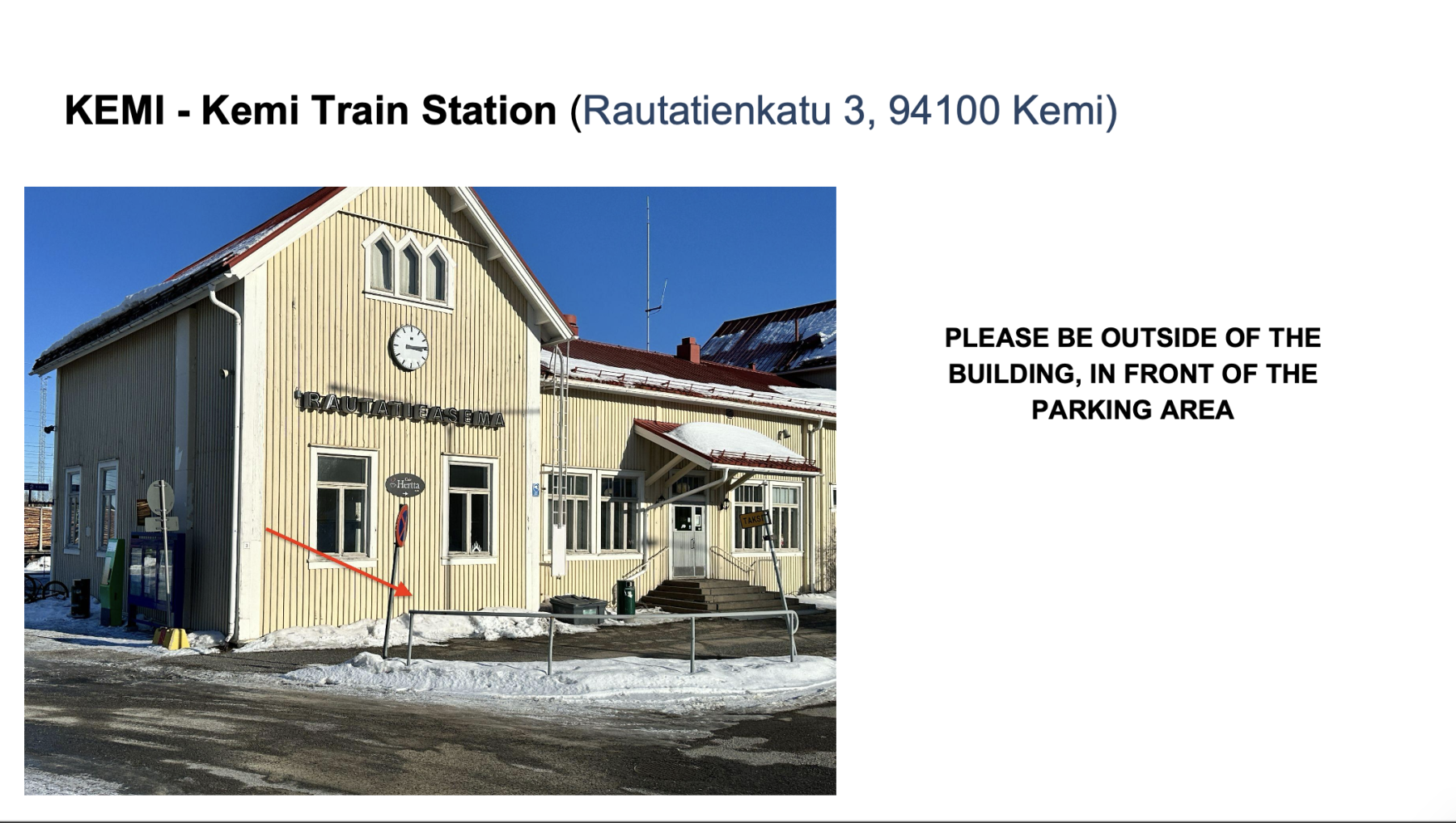 Yellow wooden building of Kemi Train Station with clock above the entrance and snow on the ground under a clear blue sky.
